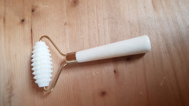 Bílý masážní váleček s bodlinkami na jedné straně